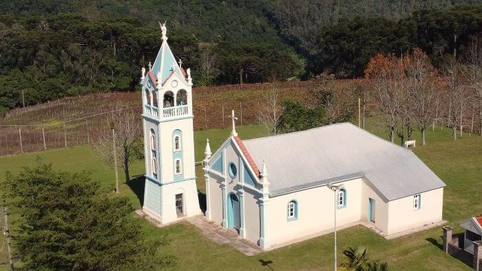 Capela branca com detalhes azuis em área rural