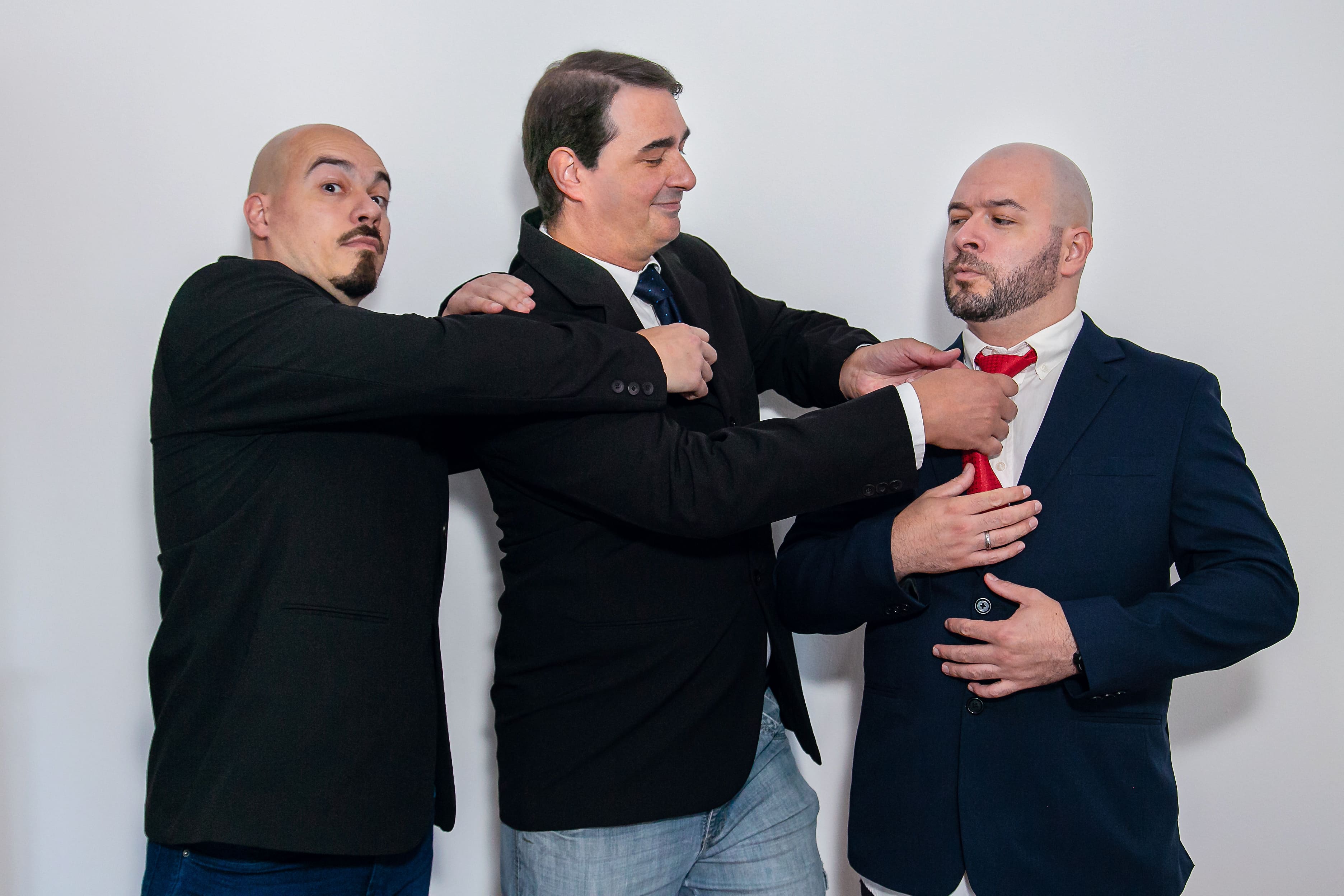 Três homens pegando na gravata um do outro