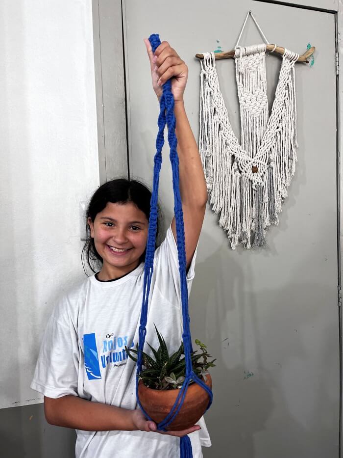 Criança segurando planta com cordão macramê