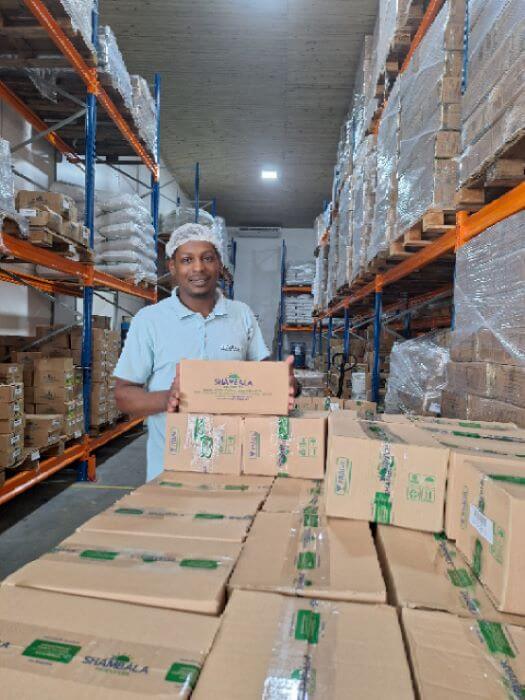 Homem em depósito sorrindo e carregando caixa