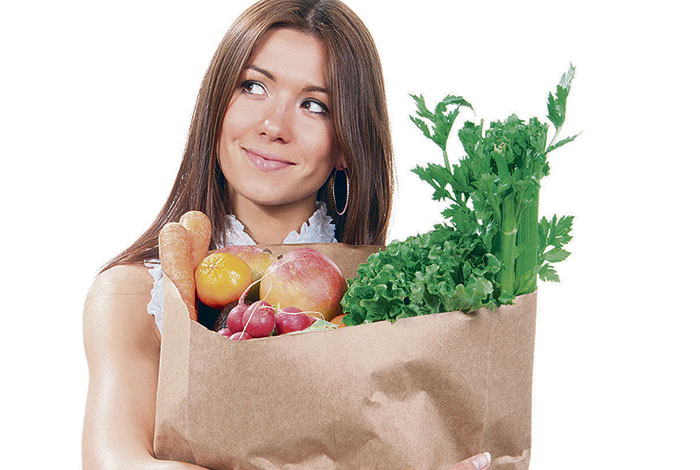 Mulher segurando saco de mercado com frutas e vegetais