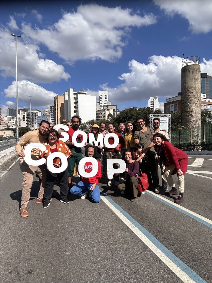Pessoas reunidas na rua com letreiro Gomo Coop