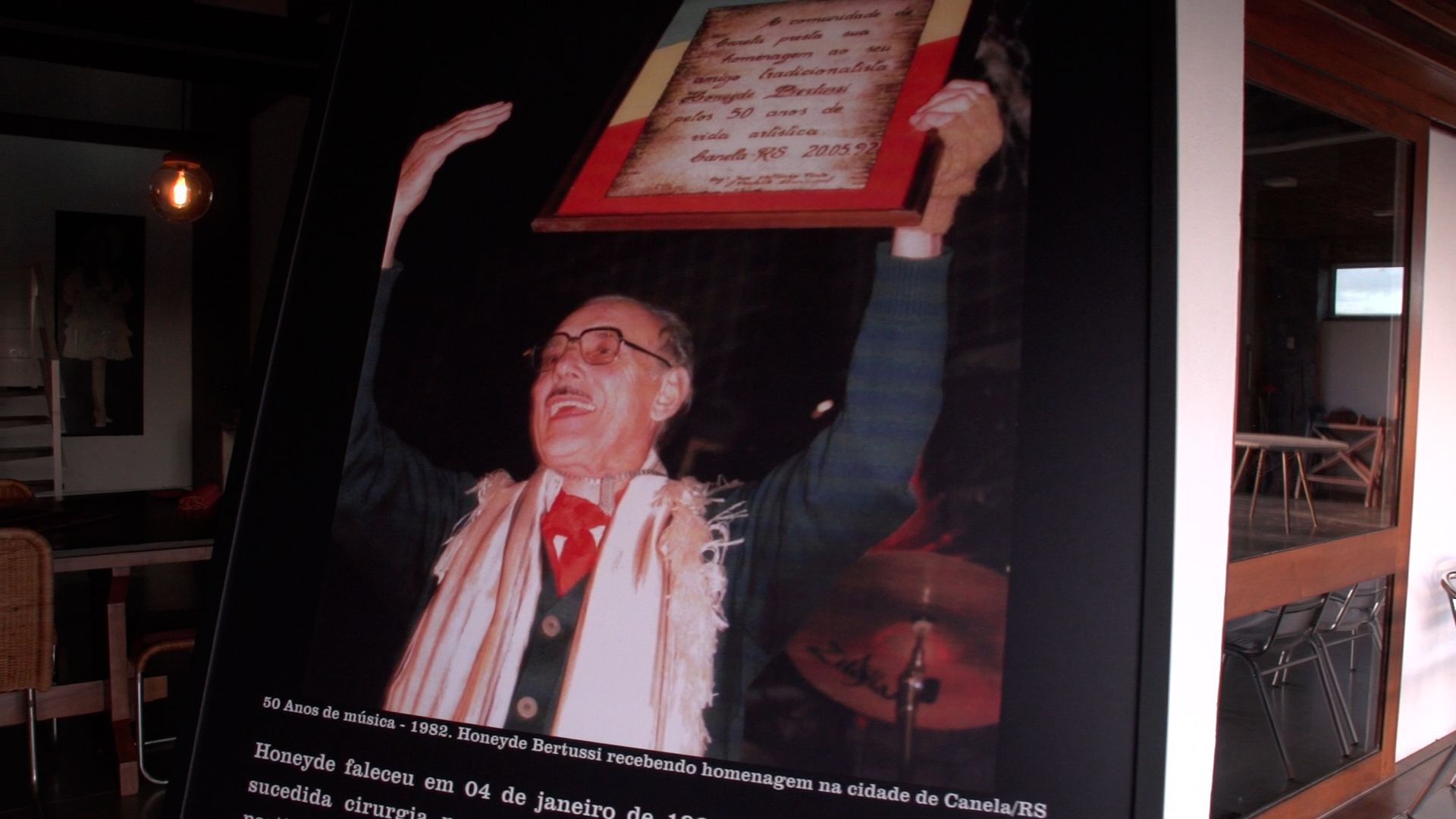 Quadro com foto antiga de Honeyde Bertussi recebendo homenagem