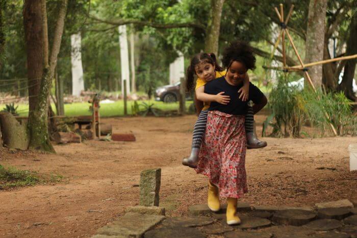 Criança nas costas de outra em floresta