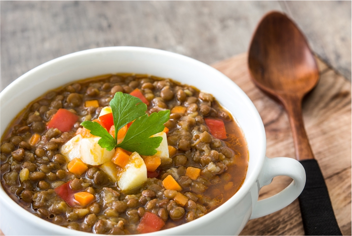 Sopa de lentilhas em travessa branca sobre a mesa