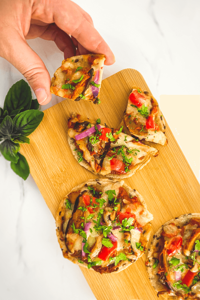 Pessoa pegando minipizzas de tábua 