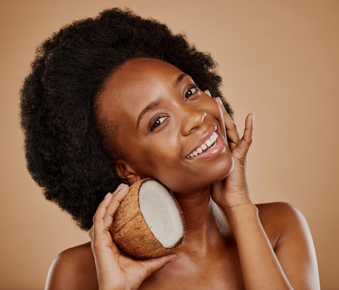 Mulher segurando coco enquanto massageia o rosto