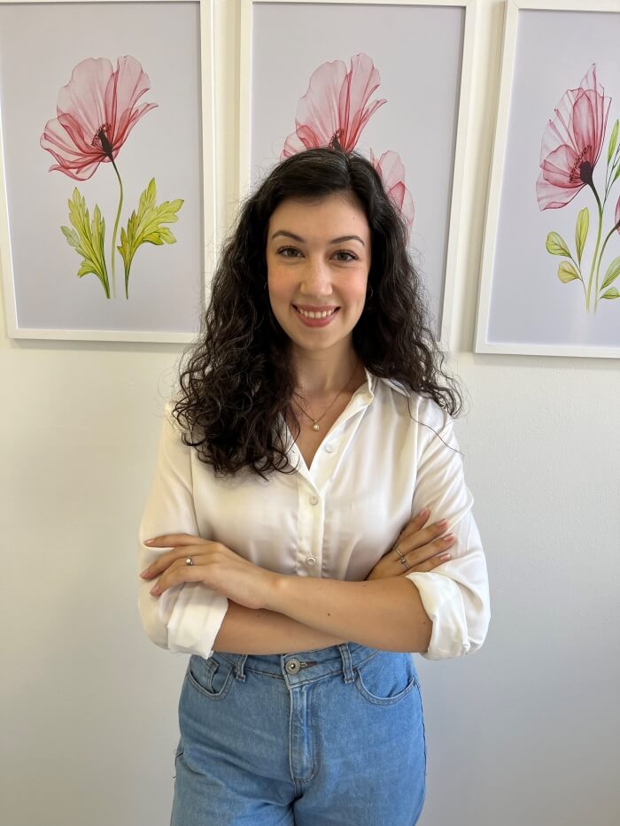 Mulher em pé, sorrindo e de braços cruzados