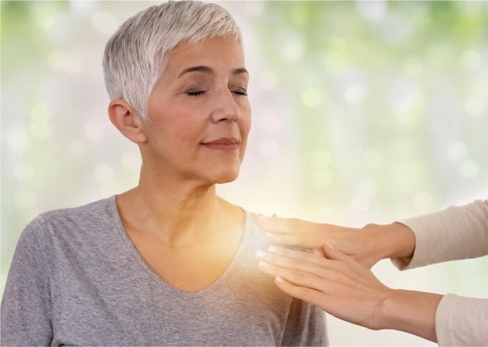 Mulher recebendo aplicação de Reiki