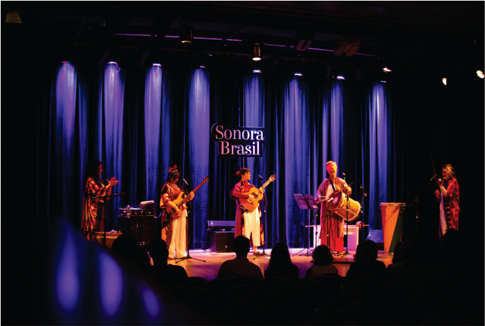 Cinco pessoas no palco tocando instrumentos