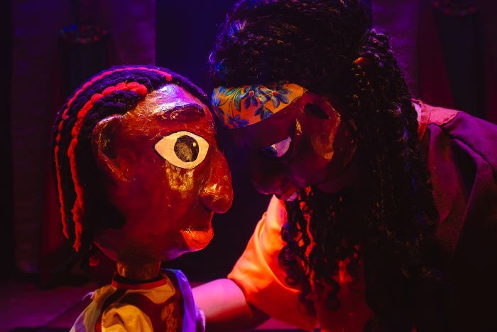 Pessoa encostando máscara em boneco tradicional