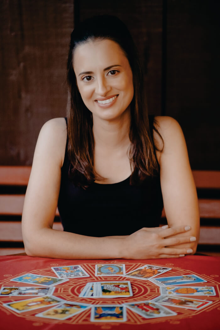 Mulher sentada atrás de mesa com várias cartas de tarô