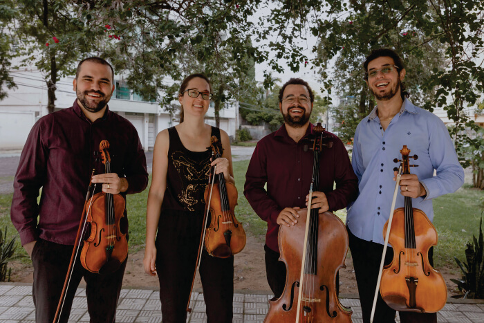 Três homens e uma mulher segurando instrumentos musicais