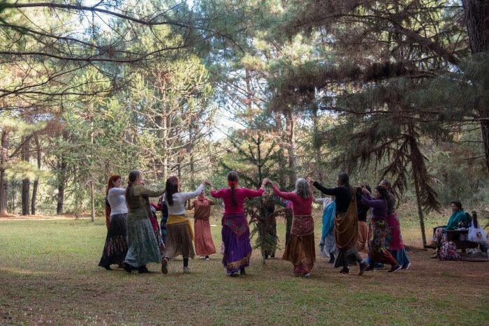 Mulheres dançando em círculo em floresta