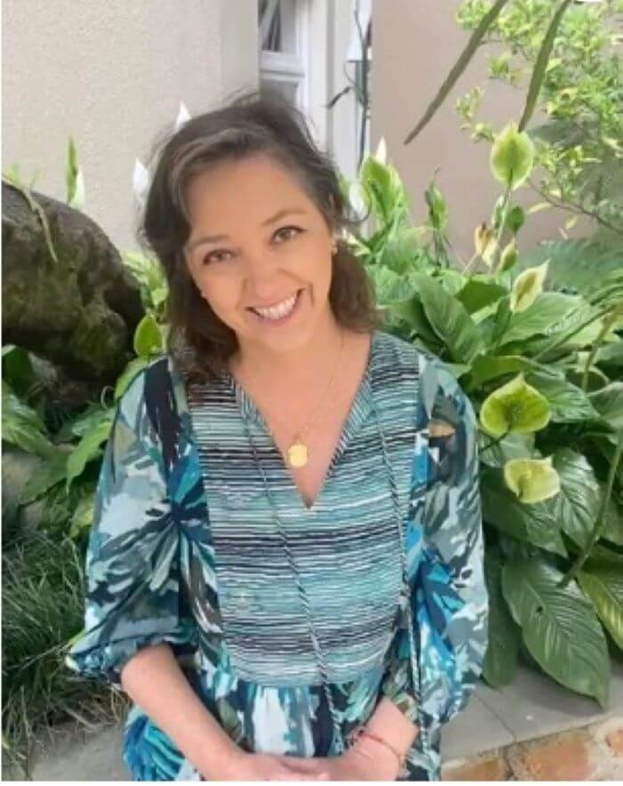 Mulher sorrindo em frente à folhagem 