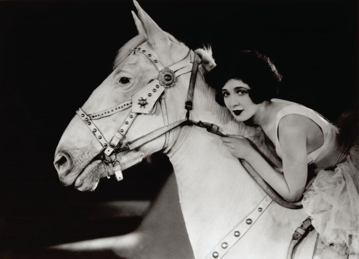 Mulher montada em cavalo branco