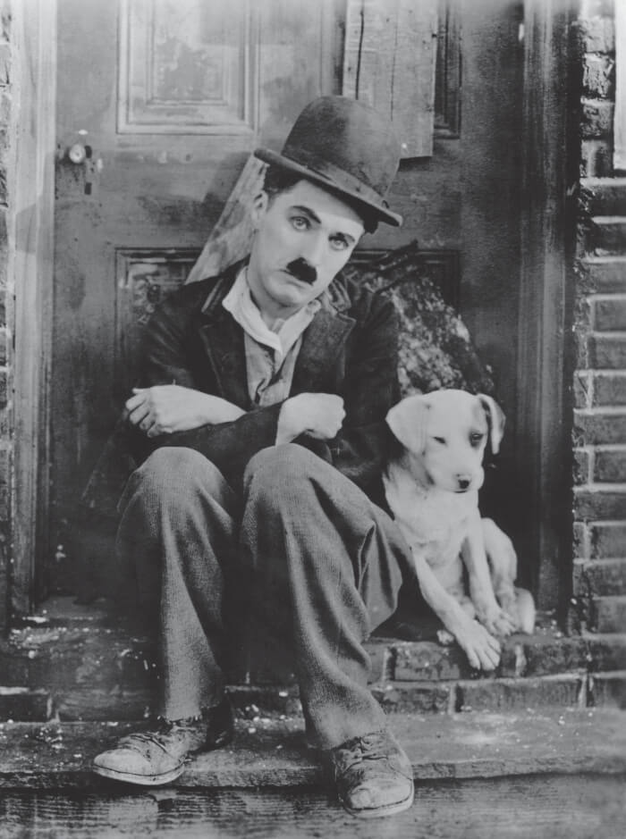 Charlie Chaplin sentado ao lado de cachorro