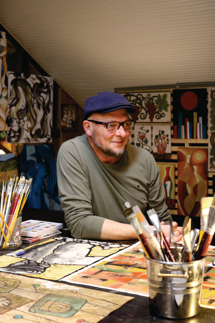Homem em frente à mesa com pinturas