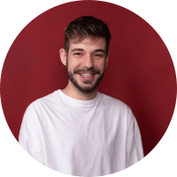 Homem de camiseta branca sorrindo em frente à parede vermelha
