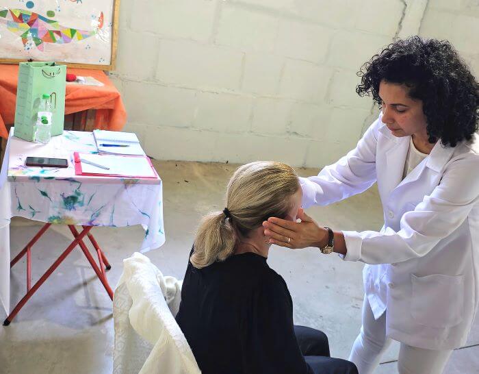 Pessoa com as mãos nas laterais da cabeça de pessoa sentada