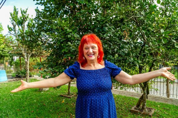Mulher em jardim com os braços abertos