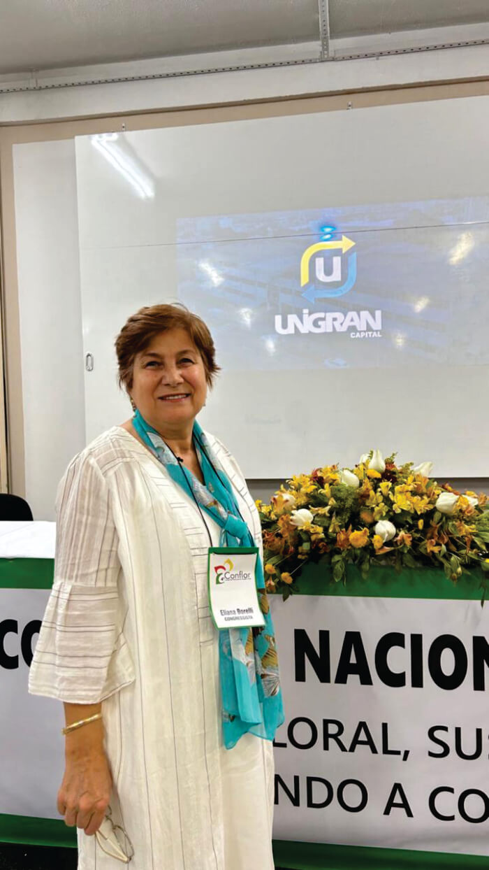 Mulher de vestido branco na frente de flores