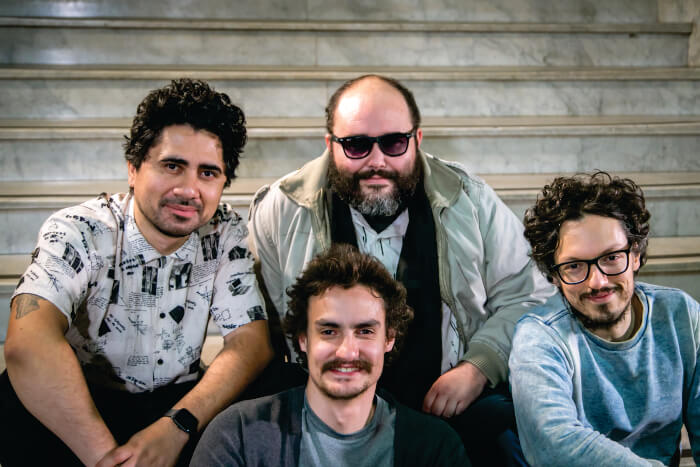 Quatro homens sentados e sorrindo
